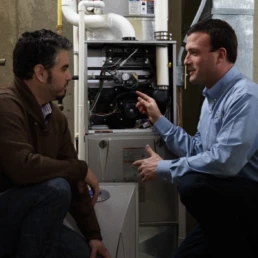 carrier tech talking with man in front of furnace